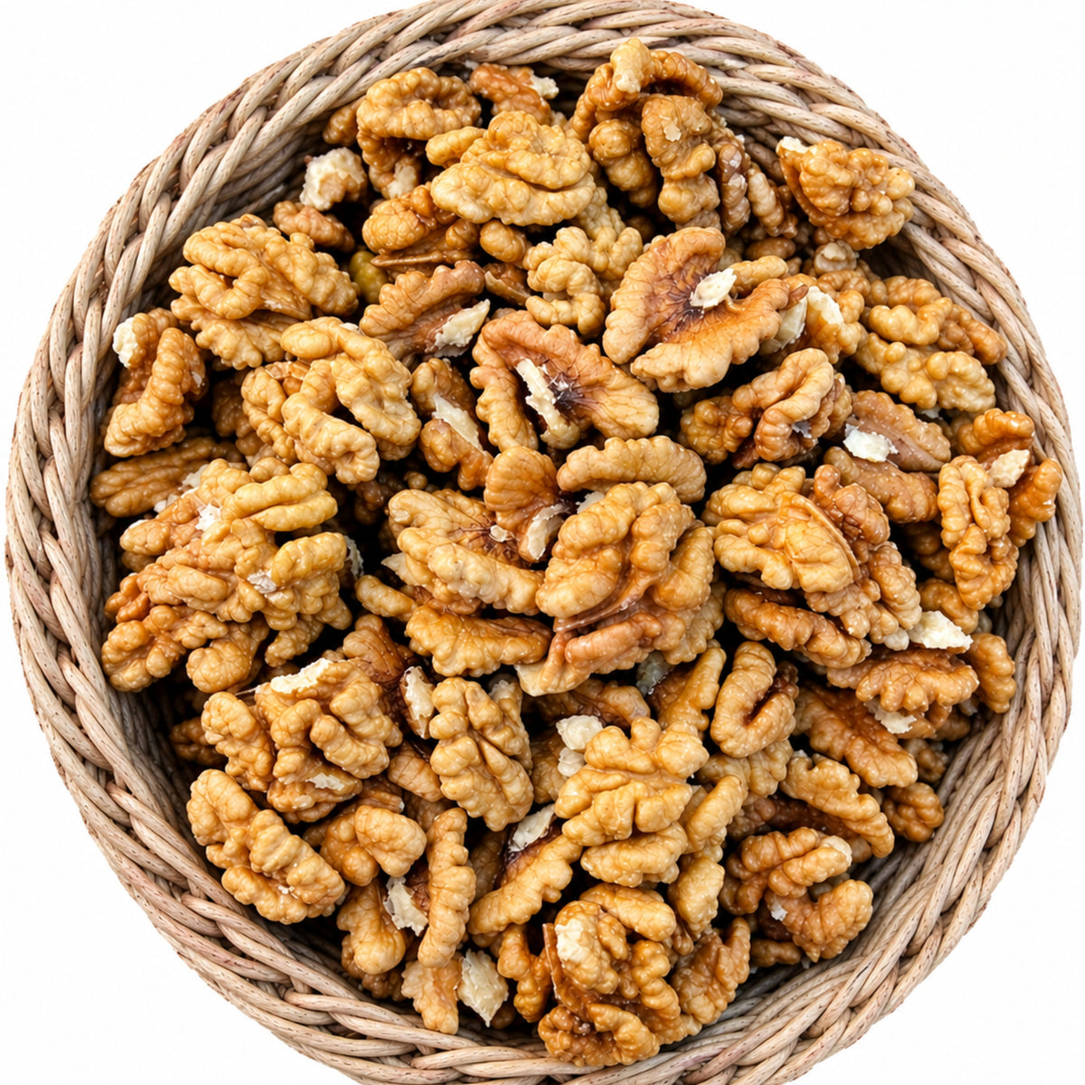 A top-down view of raw, unshelled walnuts piled inside a round woven straw basket on a solid white background.